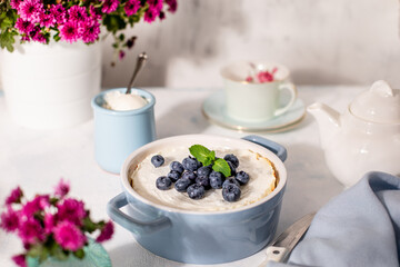 Homemade delicious Cheesecake with blueberries on a white table with shadows from the sun.