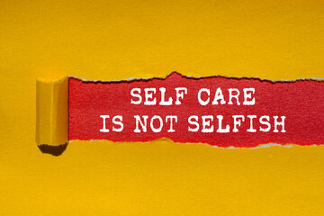 Self care is not selfish message written on ripped torn yellow paper on red background. Conceptual...