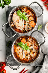 Traditional French bouillabaisse soup with fish fillets and seafood in tomato sauce. Top view.