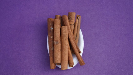 Cinnamon on a purple background in white plate.