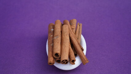 Cinnamon on a purple background in white plate.