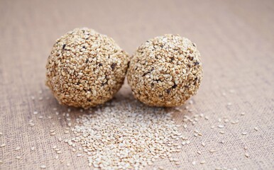 Traditional Indian sweet balls made with sesame seeds, jaggery and coconut, commonly known as Til ke laddu or sesame ladoos. Shot on brown background