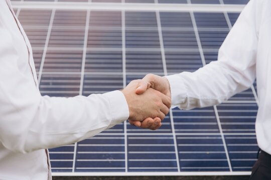 Close-up of Two Electrical Engineers shaking hands after working to inspect the installation and maintenance of solar panels in the solar power station