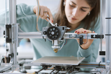 Smart female student working with a 3D printer