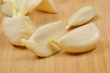 A close-up shot of fresh, peeled garlic cloves on a wooden surface, highlighting their natural texture and color