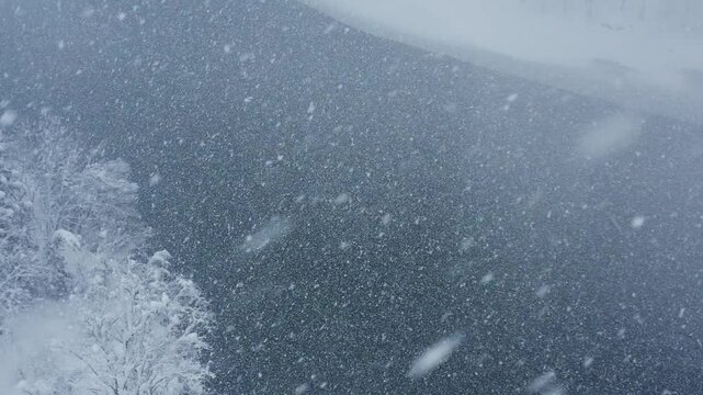 スーパースロー映像：ドローンで空撮した、大雪の日の川の上の風景
