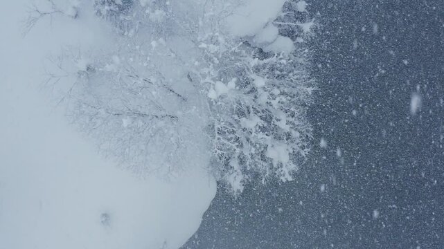 スーパースロー映像：ドローンで空撮した、大雪の日の川の上の風景
