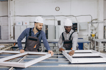Interracial factory workers assembling pvc window frames in production line