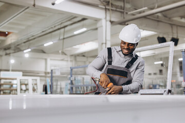 African american male factory worker assembling aluminum and PVC windows and doors