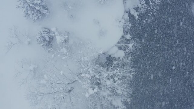 スーパースロー映像：ドローンで空撮した、大雪の日の川の上の風景