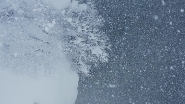 スーパースロー映像：ドローンで空撮した、大雪の日の川の上の風景