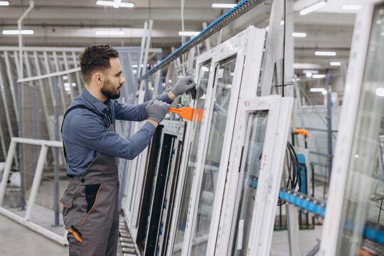 Factory worker handling PVC windows in production line