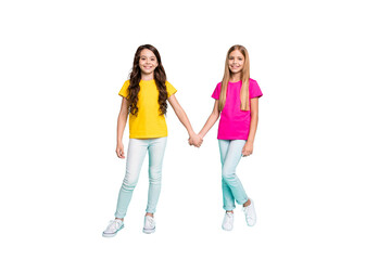 Obraz premium Full length body size photo of two nice cute beautiful kind friendly girls holding each other hands while isolated with teal background