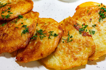 Crispy potato pancakes served with herbs on a white plate