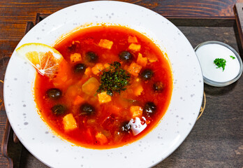 Delicious bowl of vibrant borsch with a lemon slice and garnish