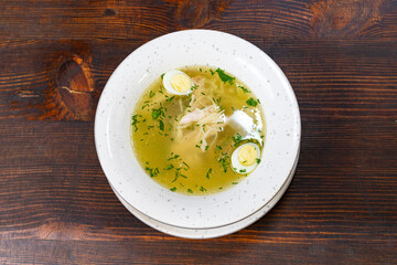 Chicken broth with fresh herbs and sliced vegetables served warm