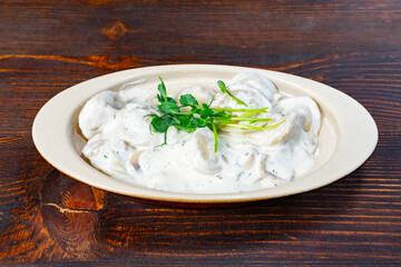 Creamy dumplings served with fresh herbs on wooden table