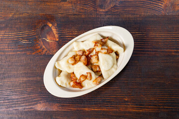 Delicious dumplings topped with crispy bacon on wooden table