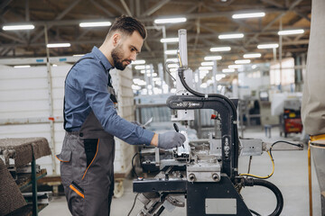 Factory male worker operating machinery producing aluminum and PVC windows and doors