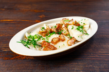 Homemade dumplings with fried meat and herbs served on wooden table