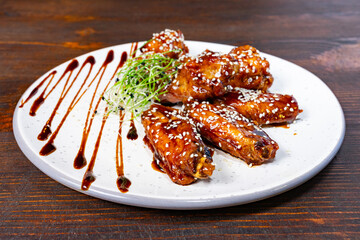 Delicious glazed chicken wings served on a white plate with garnish