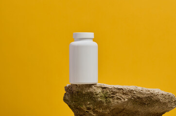 White plastic medicine jar on stone, yellow background. Mock up