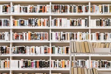 Library shelves filled with colorful books, book trolley in foreground. Concept of literature, education, public library