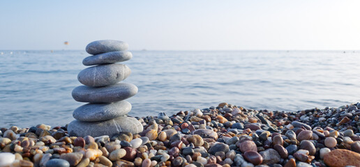 Spa stones balance on the sand of the beach.