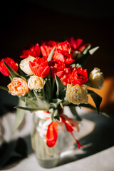 Vase of colorful tulips by a sunlit mirror celebrating the beauty of spring in a cozy interior setting