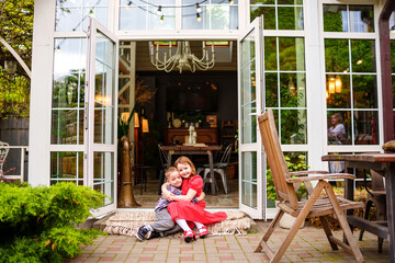 Obraz premium Cute and happy brother and sister sitting on the porch of a country house. 