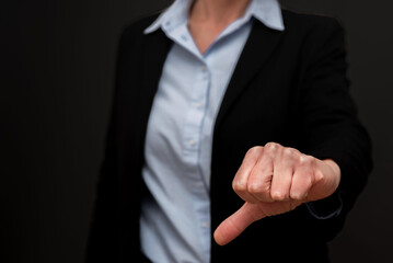 Close up of Businesswoman showing thumbs down in disapproval, expressing negative feedback on a black background