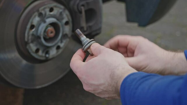  A tire fitter greases the bolts and holes before installing a wheel. The grease prevents metal corrosion and helps loosen or tighten bolts or nuts.