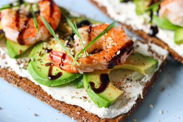 Delicious open-faced sandwich with creamy cheese, avocado, shrimp, and balsamic glaze on whole-grain bread. It is topped with sesame, smoked paprika, and wheat microgreens. A perfect seafood appetizer