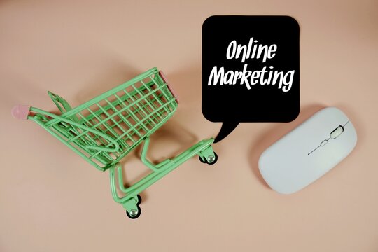 Online Marketing text on speech bubble with optical mouse and trolley shopping cart on pink background