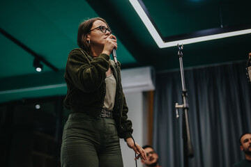 A young woman passionately sings into a microphone in a modern studio setting. The image evokes creativity, music, and the collaborative atmosphere of creating art. A thoughtful moment captured during