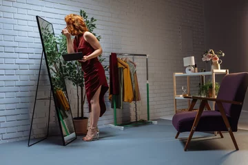 Fotobehang Fashion designer applying makeup looking in the mirror in her studio © bernardbodo