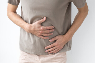 A man clutching his stomach in pain, possibly experiencing digestive issues, cramps, or discomfort related to health problems, Faceless
