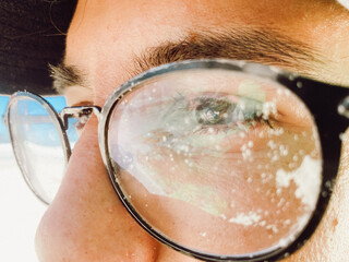 Close-up de un chico mirando el mar con lentes viejos llenos de arena de playa de brasil 