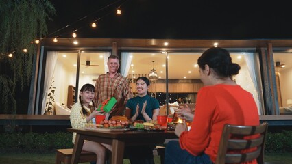 Family together celebrate anniversary in garden. Senior give gift to granddaughter. Outdoor camping activity to relax with relatives, spend time with multigeneration cross generation gap. Divergence.