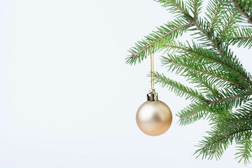 Single gold Christmas glass ball hanging from a pinay brunch, isolated on the white.