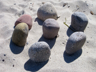 vom Meer rundgeschliffene Steine liegen in einem Kreis im Sand