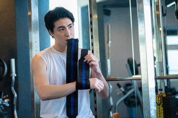 Fototapeta premium ジムでサポーターをつけて準備をする日本人男性