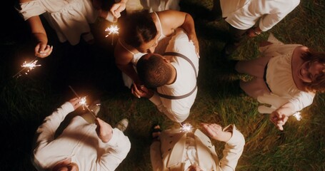 Guests with sparklers dancing around the bride and groom, outdoor wedding, top view