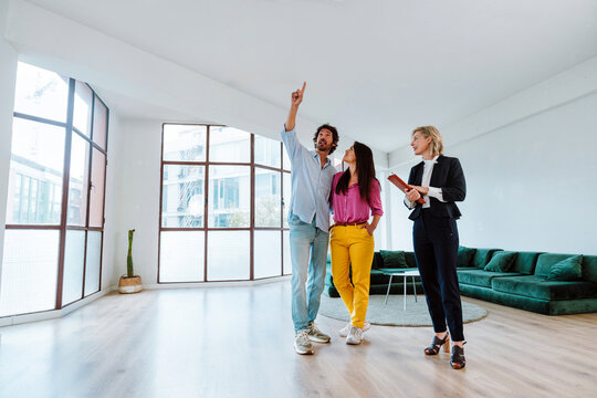 Real estate agent showing a new apartment and features of a good investment to a young couple. Woman and man buying a property in a rich area of the city.