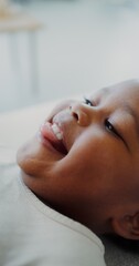 Close-up of a smiling face of an African-American child while playing with his mother lying on the...