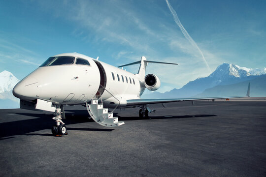 private jet airplane on the ground waiting to be boarded snowy mountains in the background	
