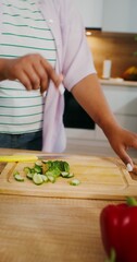 Mom and daughter cook in the kitchen slicing vegetables for salad. Hands close-up, not faces