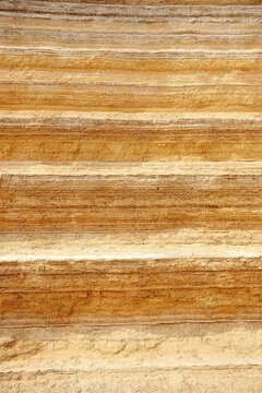 Rammed earth wall, compact layers, natural material, sandy texture, earthy tones create a warm, organic feel.