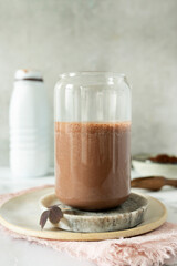 A glass of cocoa milkshake paired with a plastic bottle of protein supplement, combining taste and health.