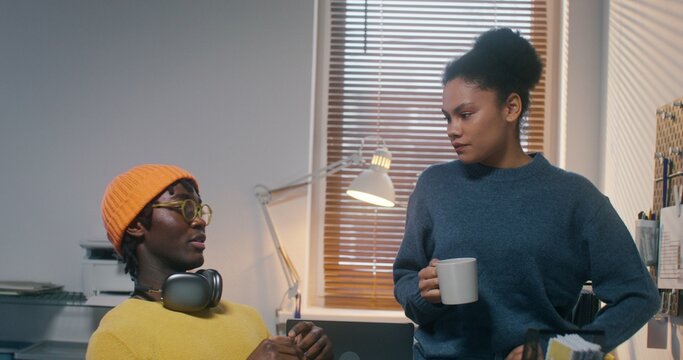 A man and a woman drink coffee and talk during a break in the office